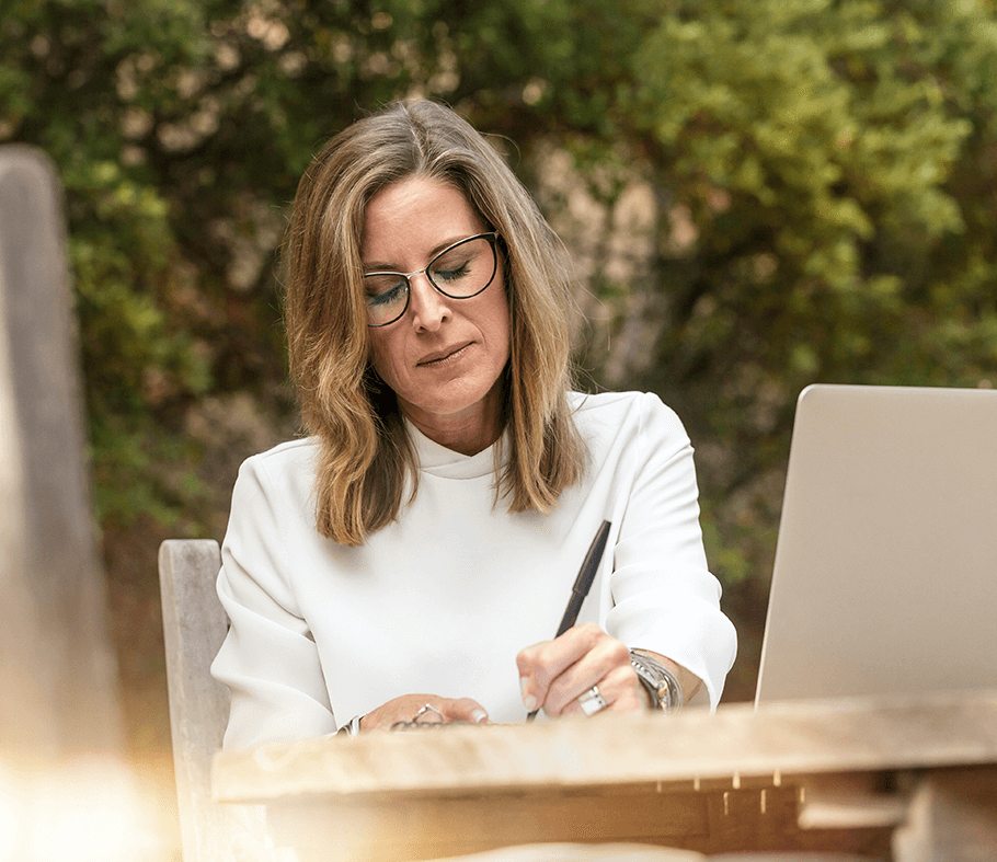 a photo of a white woman writing on a notebook